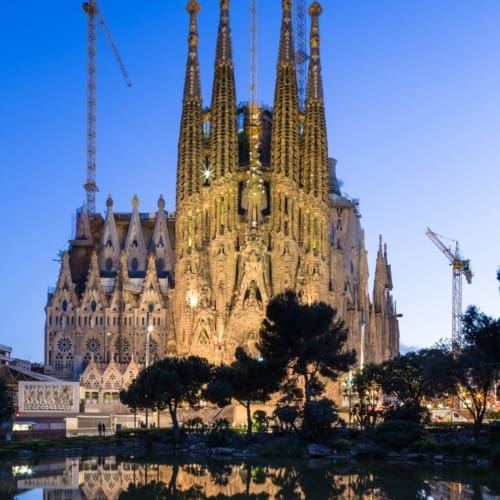 Dusk view of the Nativity Facade of La Sagra Familia basilica reflected in the lake of the Placa de Gaudi, Barcelona, Spain. BC014