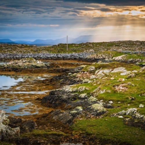 Sunburst over the Connemara mountains from Rossadillisk, County Galway.