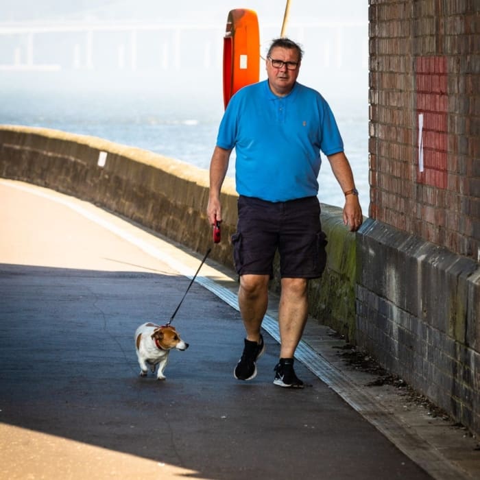 Man and dog walking under the Tay Railway Bridge, Dundee, Scotland. DD085