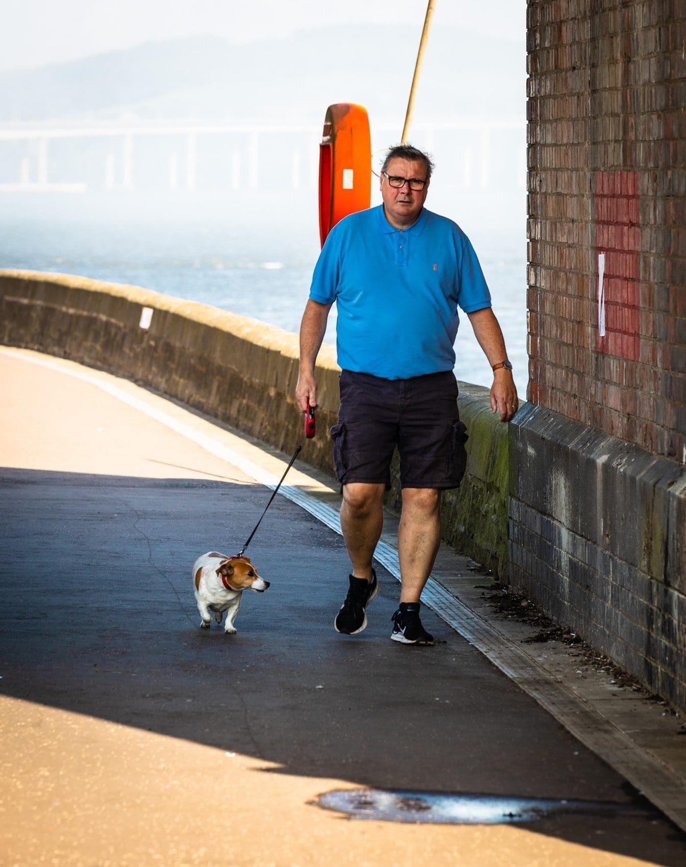 Man and dog walking under the Tay Railway Bridge, Dundee, Scotland. DD085