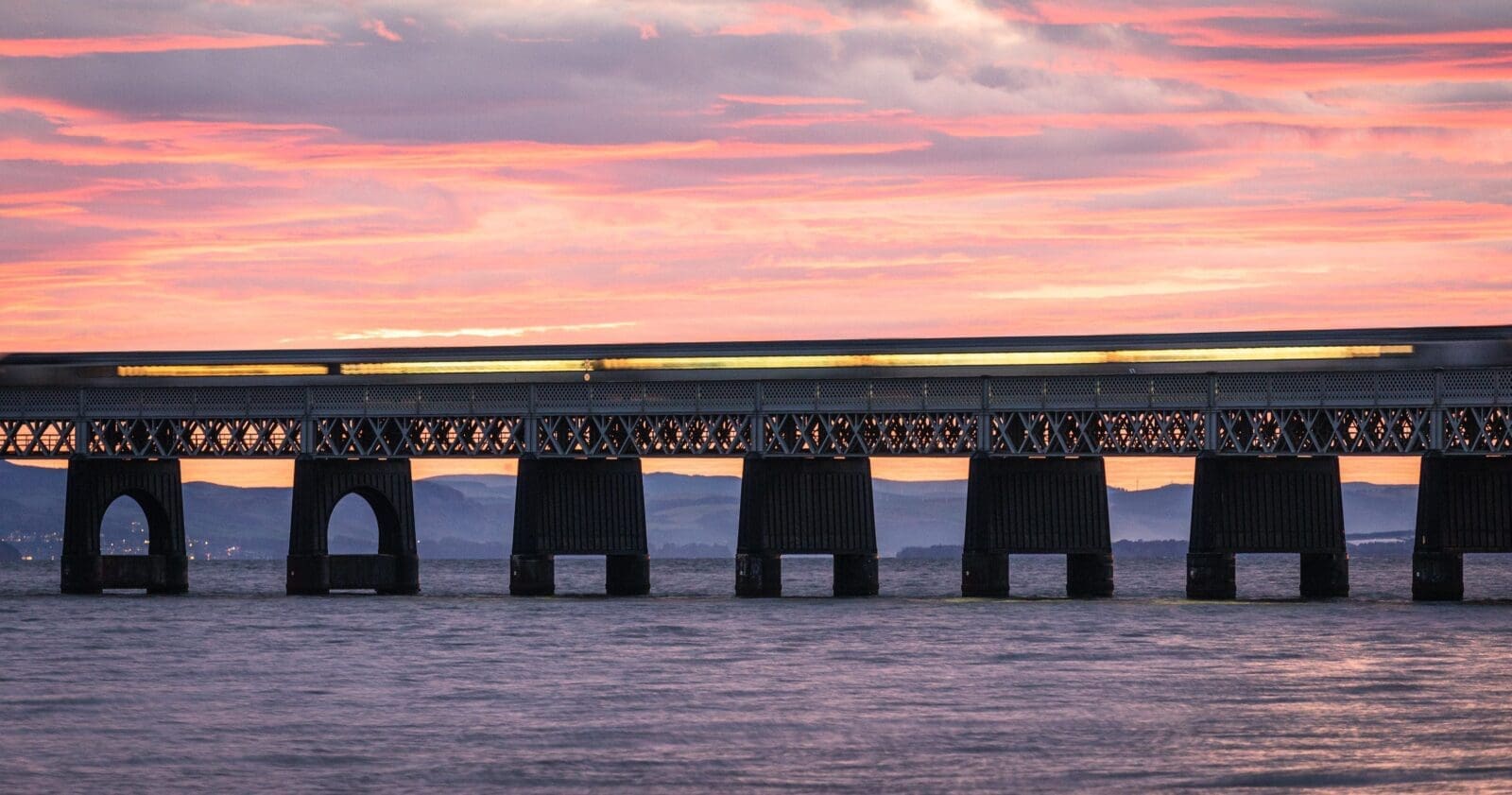 Train passing over the Tay Railway Bridge at sunset, Dundee, Scotland.