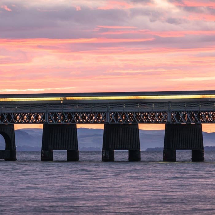 Train passing over the Tay Railway Bridge at sunset, Dundee, Scotland.