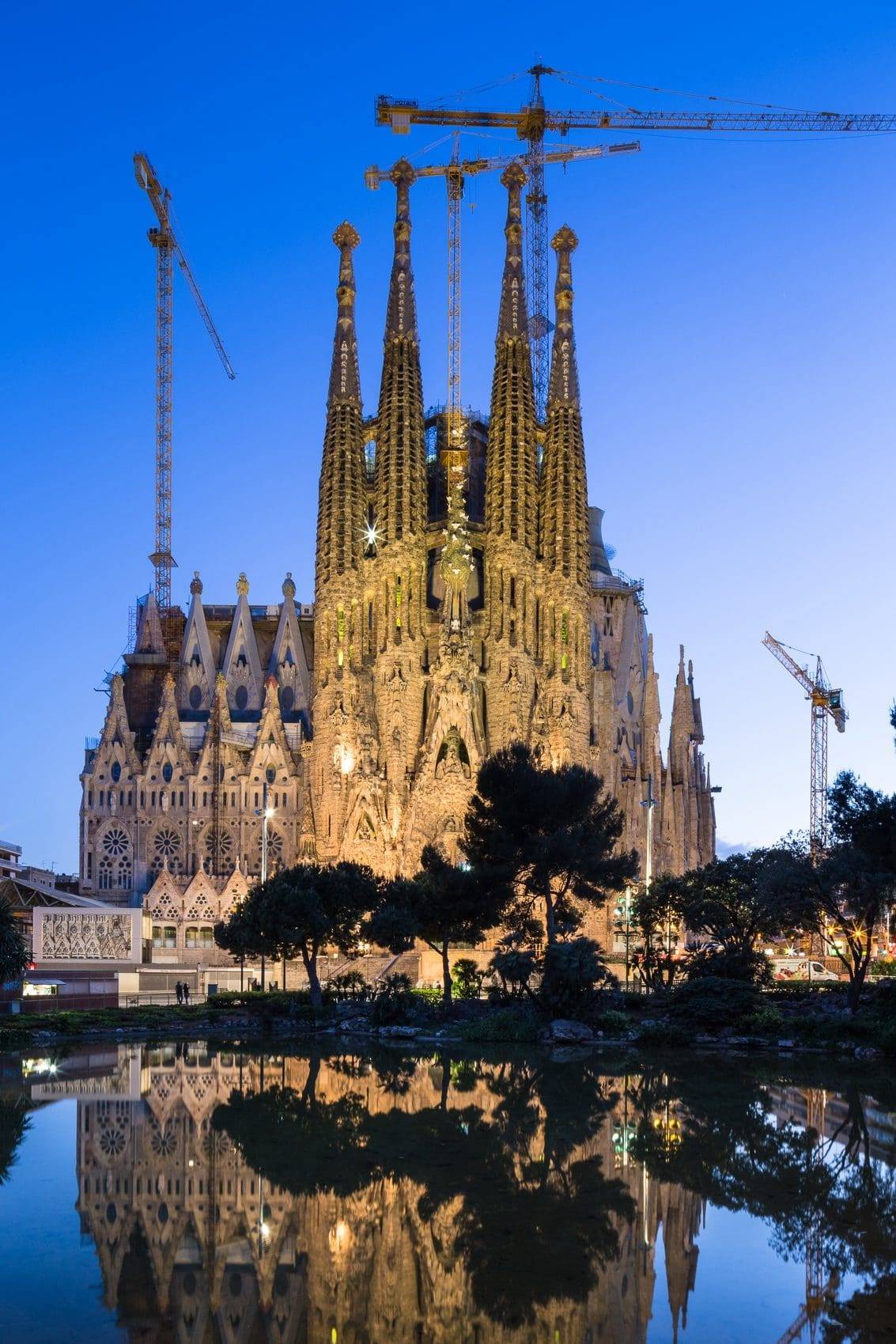 Dusk view of  the Nativity Facade of La Sagra Familia basilica reflected in the lake of the Placa de Gaudi, Barcelona, Spain. BC014